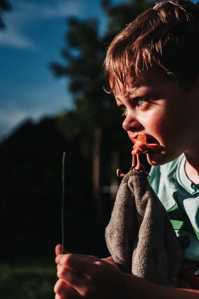 Jong kind met een grasspriet in de hand, vastgelegd in een stil en aandachtig moment buiten
