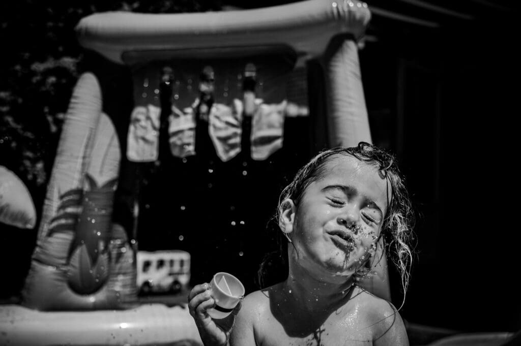 Kind speelt met water op een zomerse dag, vastgelegd in een spontaan en ongefilterd moment