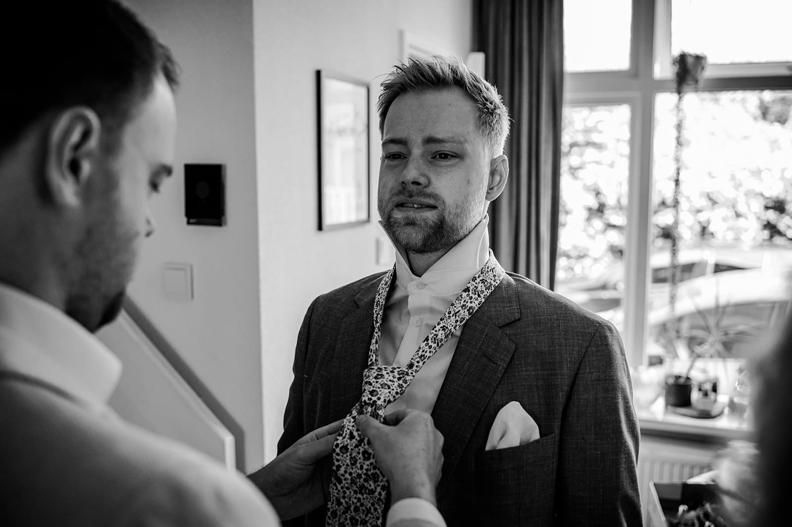 Bruidegom wordt geholpen met zijn das tijdens de voorbereidingen op de trouwdag in Schalkhaar