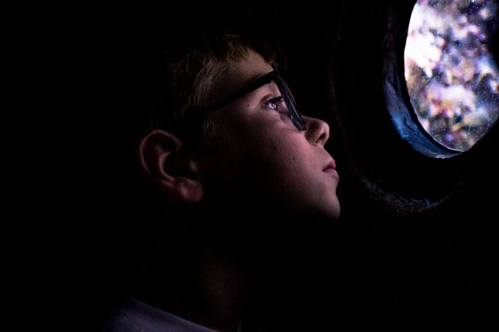 Kind kijkt geconcentreerd naar licht en reflectie, vastgelegd in een rustig en intiem moment